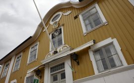 Bild på rådhuset i Ulricehamn. En gul träbyggnad med vita fönster.