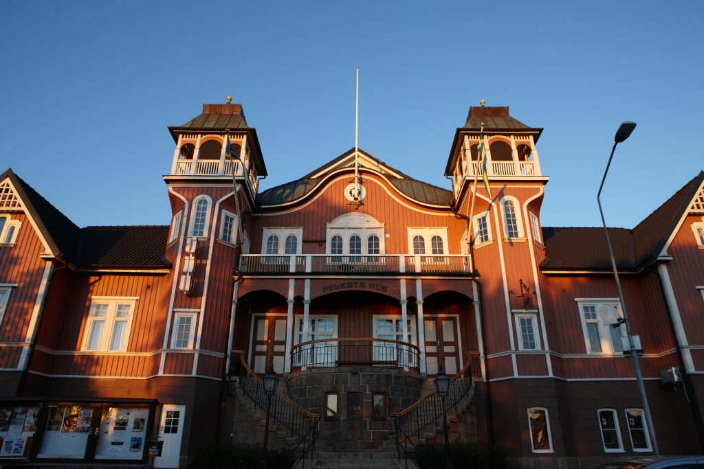 Bild på Folkets hus i Ulricehamn, en rosafärgad träbyggnad med hög stentrappa och två torn.