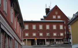 Bild på stadshuset taget från Bogesundsgatan. Huset är en röd tegelbyggnad i vinkel och i flera våningar.