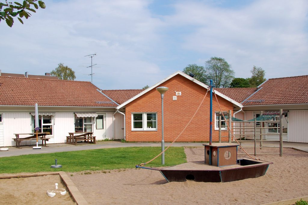 Bild på Pastellens förskola och skolgården med sandlåda med en båt i förgrunden