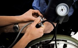 En person tar blodtrycket på en person i rullstol