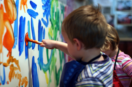 Bild på en tre-åring som målar på en vägg med blått och orange