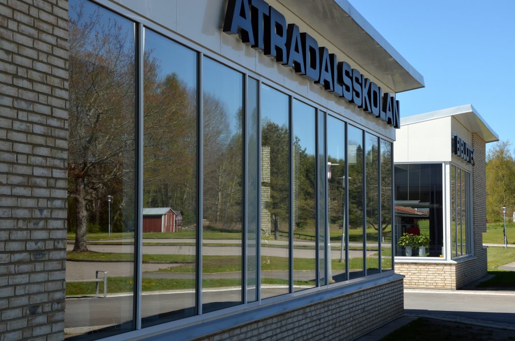 Bild på glasparti på Ätradalsskolan. på bilden ses också en fasadskylt med skolans namn.