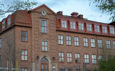 Bild på Bogesundsskolans övre skola. En stor tegelbyggnad i rött med flera våningar