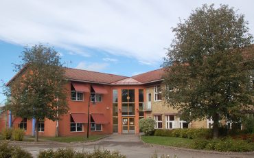 Bild på Hökerums skola som har två våningar och är byggd i terrakottafärgad och beige puts