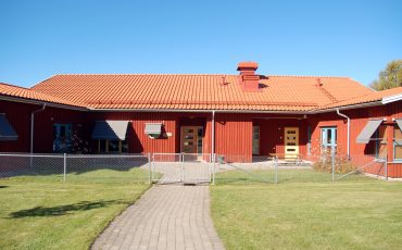 Bild på Marbäcks förskola som är en enplanshus i rött trä byggt i vinkel..