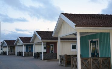 Bild på Ulrikaskolans ingångar på baksidan av husen som är i ljusgult trä.
