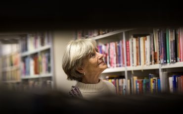 Kvinna bland böcker och bokhyllor på biblioteket.