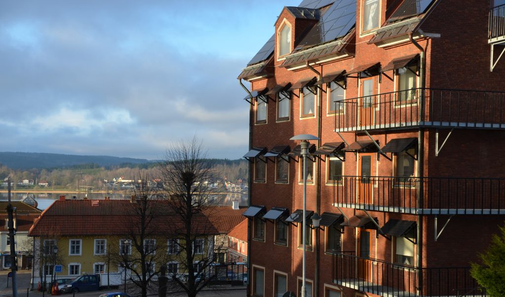 Bild på stadshuset i Ulricehamn, en röd tegelbyggnad i flera våningar med staden i bakgrunden