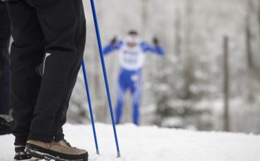 Längdskidåkare och publik med stavar.