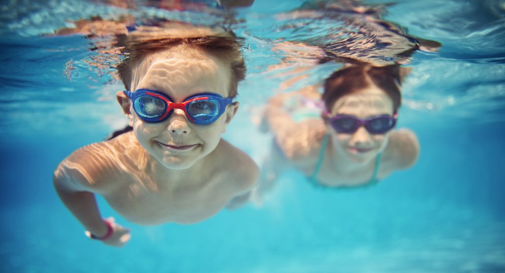 en flick och en pojke som simmar i en pool