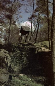 En bild på en Klockstapel och träd runt omkring.