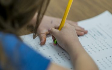 Bild på barn som fyller i ett prov med en blyertspenna