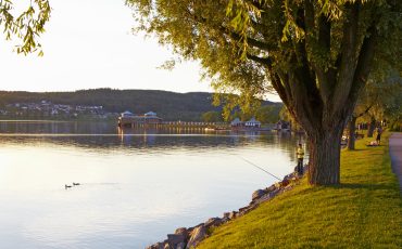 Bild på strandpromenaden vid sjön Åsunden som ligger spegelblank.