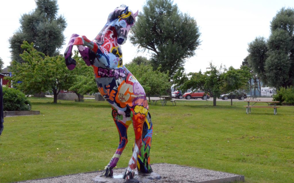 En bild på en flerfärgad hästskulptur, Leone i Sjöträdgården i Ulricehamn.