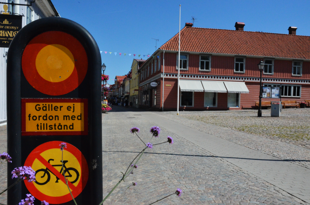 Bild på en vägskylt med förbud för cykeltrafik och motorfordon. i bakgrunden stora torget och gågatan i Ulricehamn.