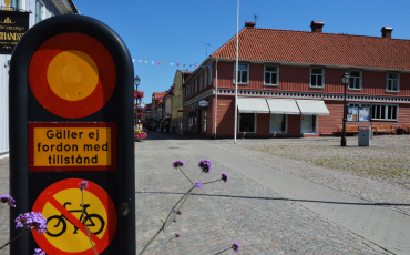 Bild på en vägskylt med förbud för cykeltrafik och motorfordon. i bakgrunden stora torget och gågatan i Ulricehamn.