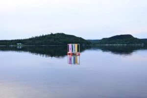 Bild på Colour in waves, en konstinstallation med en flotte med en färggrant segel ute i Åsunden