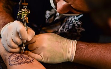 Bild på en person som gör en tatuering på en annan persons arm