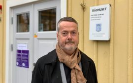 Gustaf Olsson framför rådhusets gula fasad