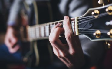 En bild på en gitarrhals och en hand som tar ett ackord