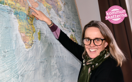Karin har glasögon och pekar ut Eritrea på en stor världskarta som sitter på väggen.