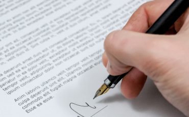 Hand som skriver under ett dokument