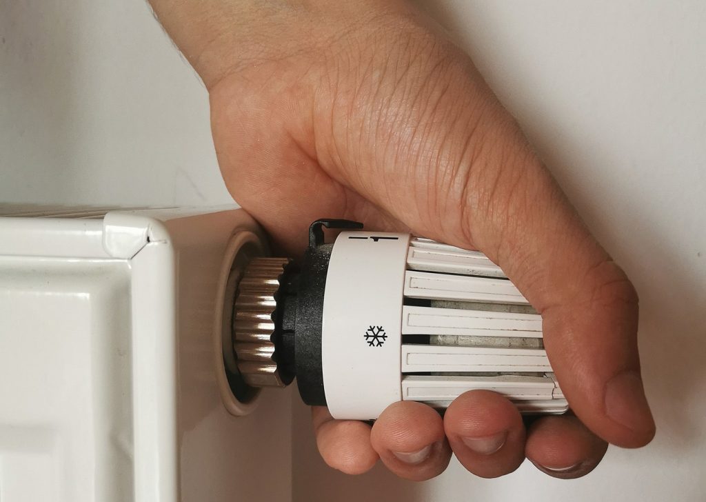 En hand skruvar på termostaten på ett element