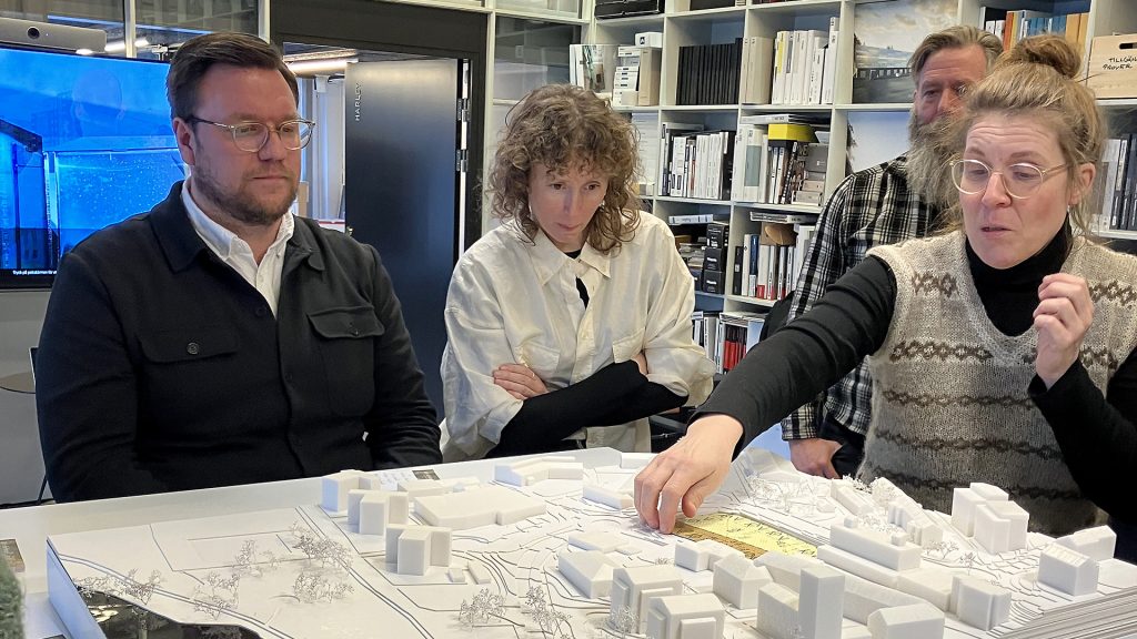 Tre personer tittar på modell föreställande en del av en stad