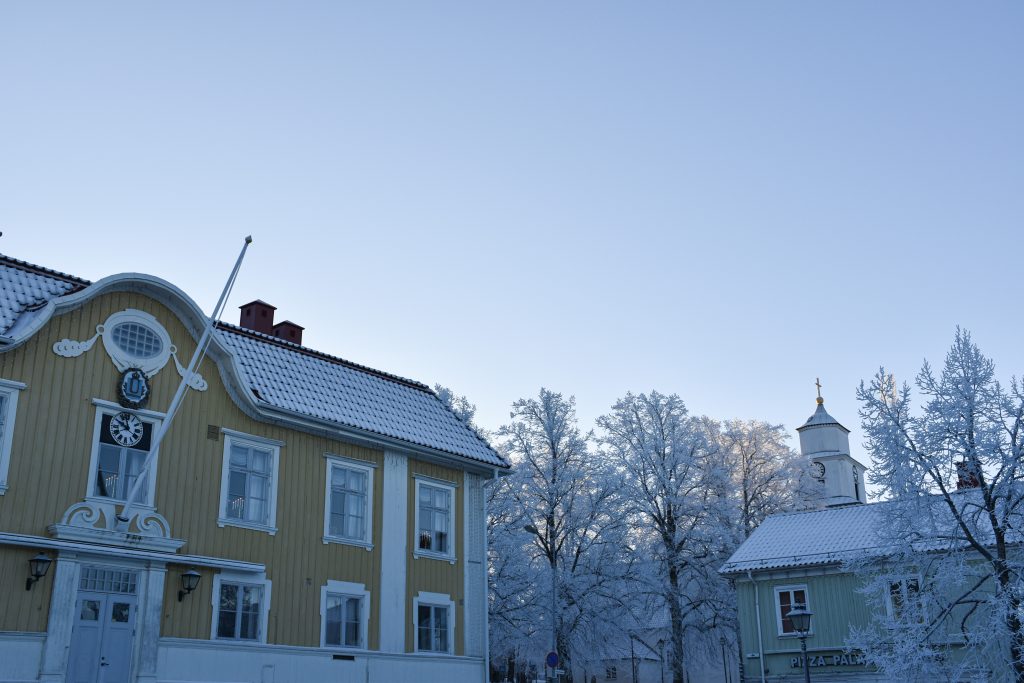 gult hus i vinter, snö på taken och på marken