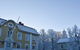 gult hus i vinter, snö på taken och på marken