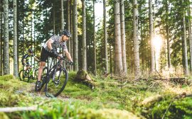 Två personer som cyklar mountainbike i kuperad terräng.