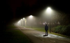 En person går på en dåligt upplyst väg.